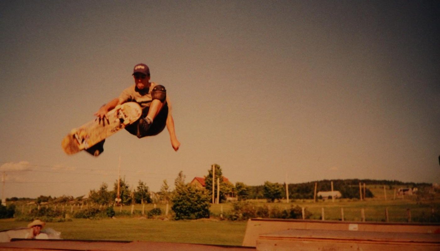 A teenage Micah airs off a plywood mini-ramp in a field in Saint-Romain, shot on film