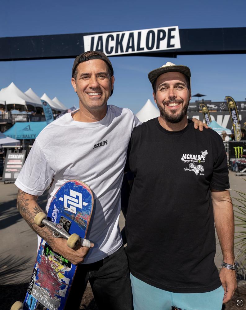 Bob Burnquist and Micah Desforges smiling under a JACKALOPE banner at Virginia Beach