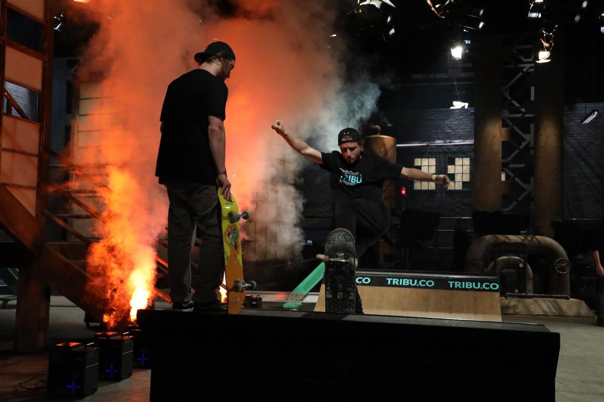A skater in a TRIBU shirt grinds a rail through pyro on the Dragons' Den set