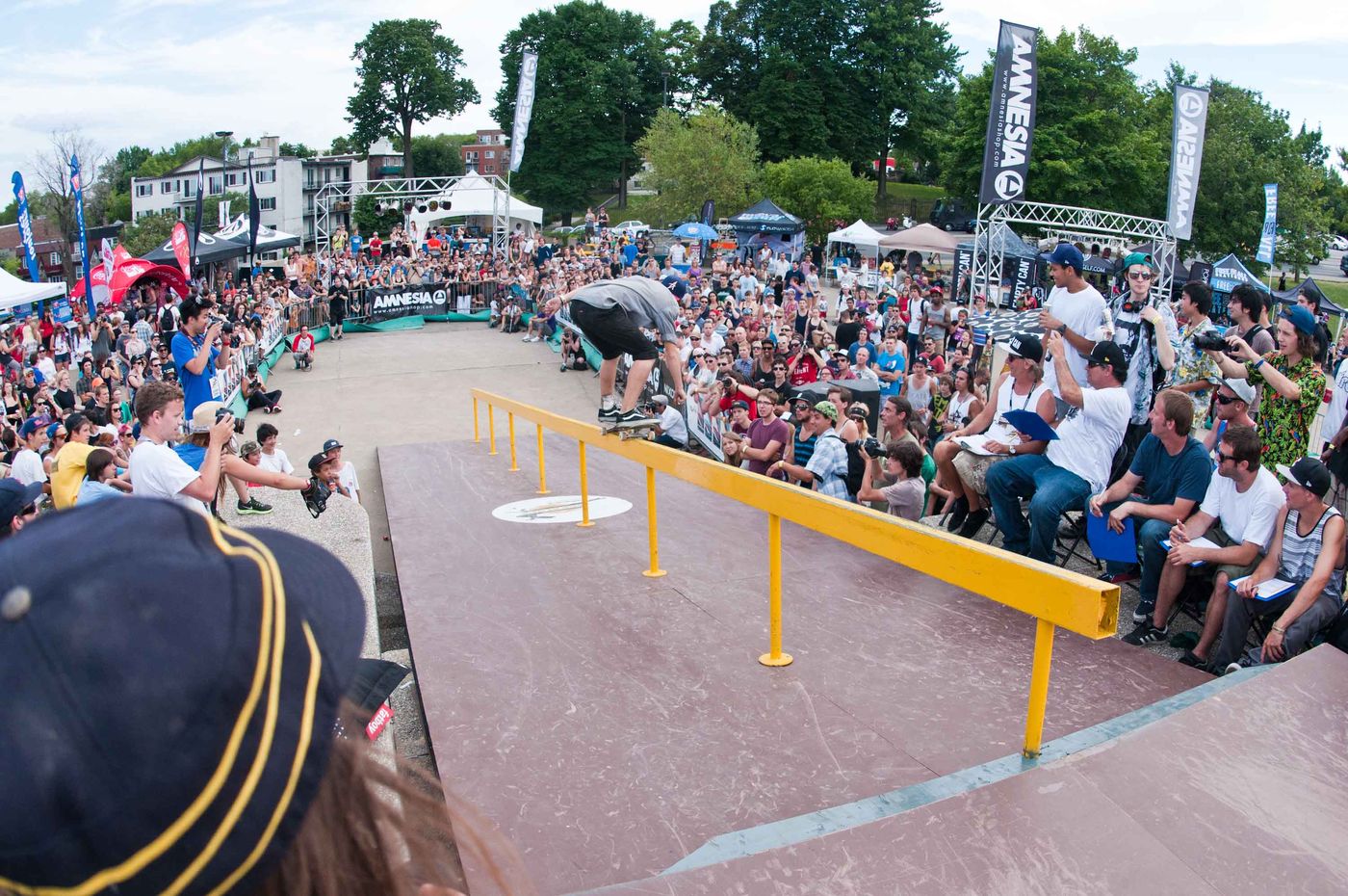 A skater grinds the yellow rail in front of a packed crowd and a row of judges at the first Jackalope, Olympic Park, 2012