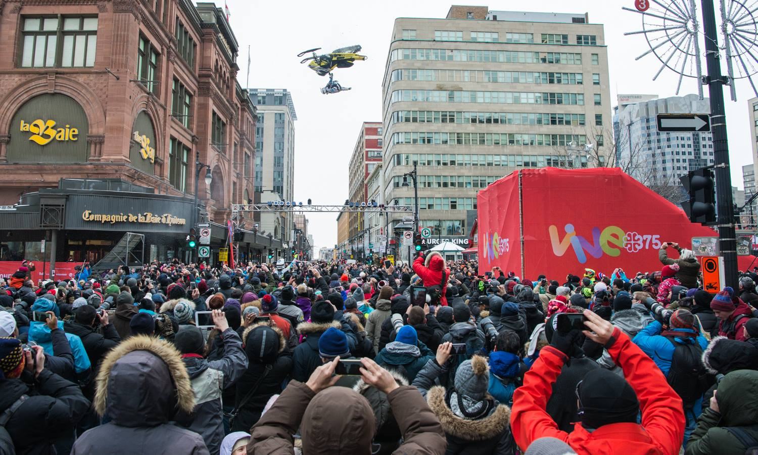 A freestyle snowmobile flying above thousands of spectators on Sainte-Catherine Street for Montréal's 375th