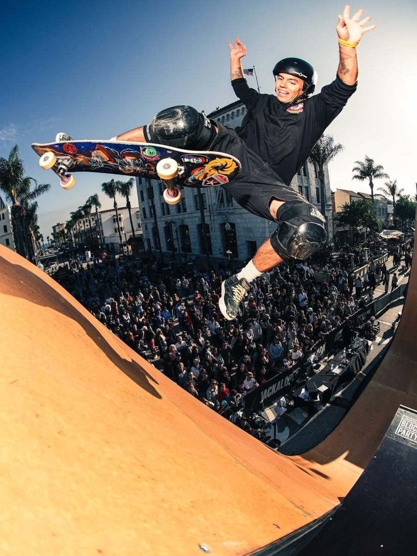 A skater flies out of the vert ramp above the Ventura Block Party crowd, city hall and palms behind